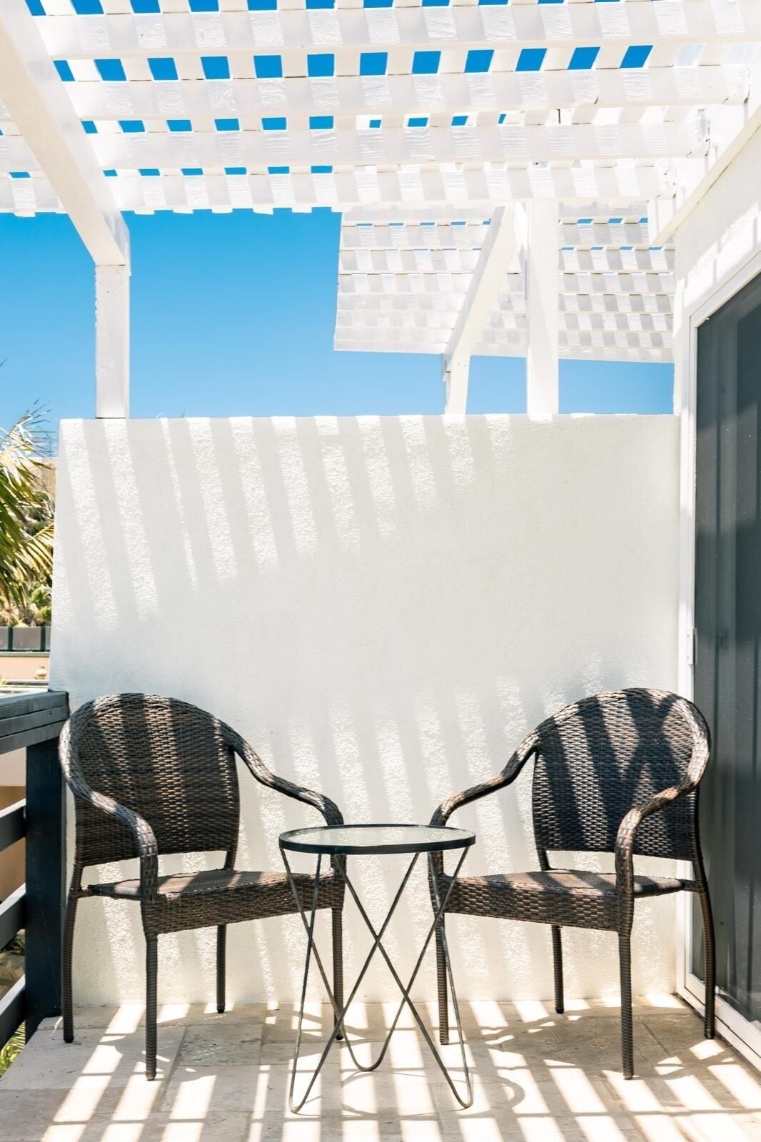 A covered patio area with two wicker chairs and a small table.
