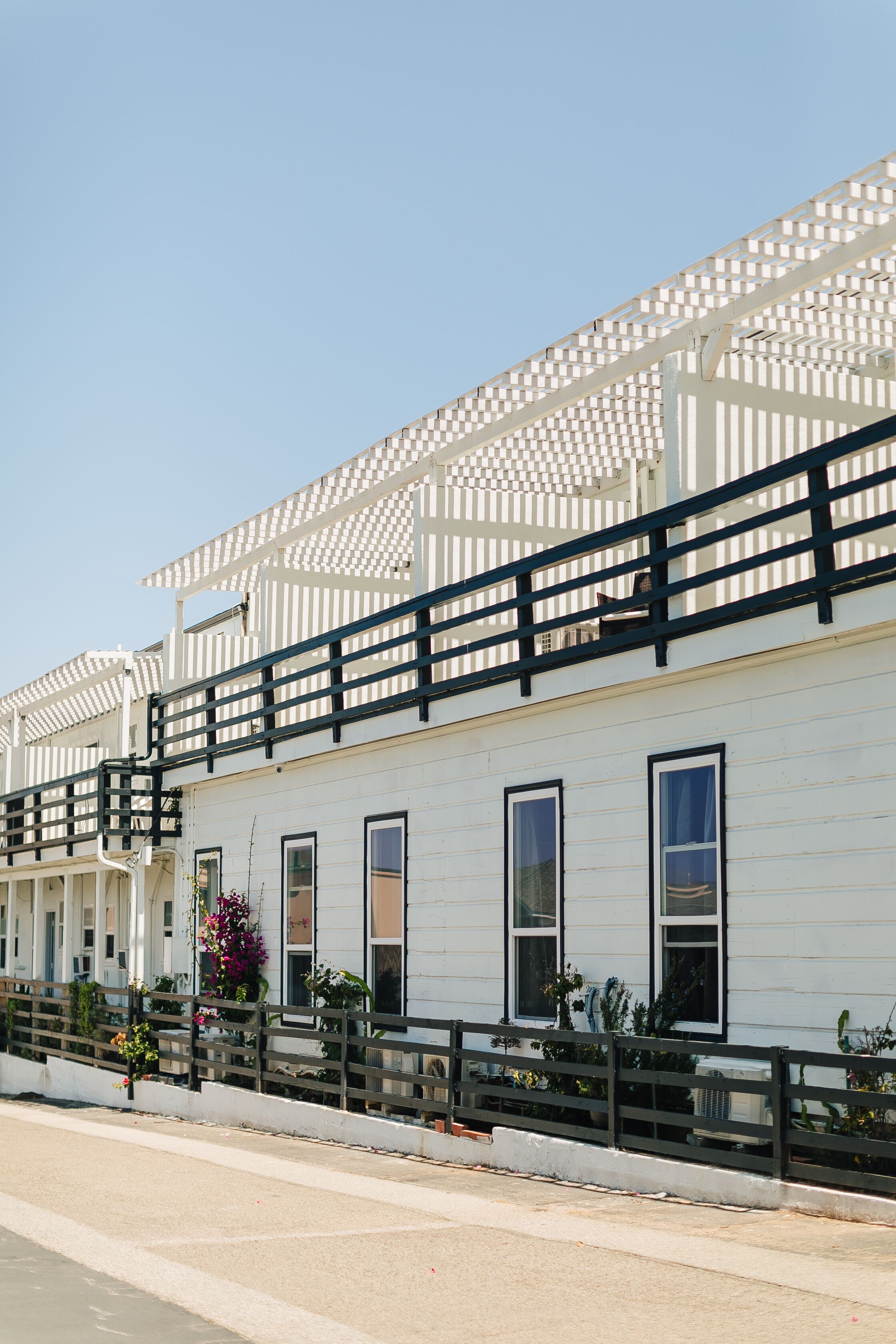 A white building with multiple windows and balconies, featuring a checkered pattern on the upper level.