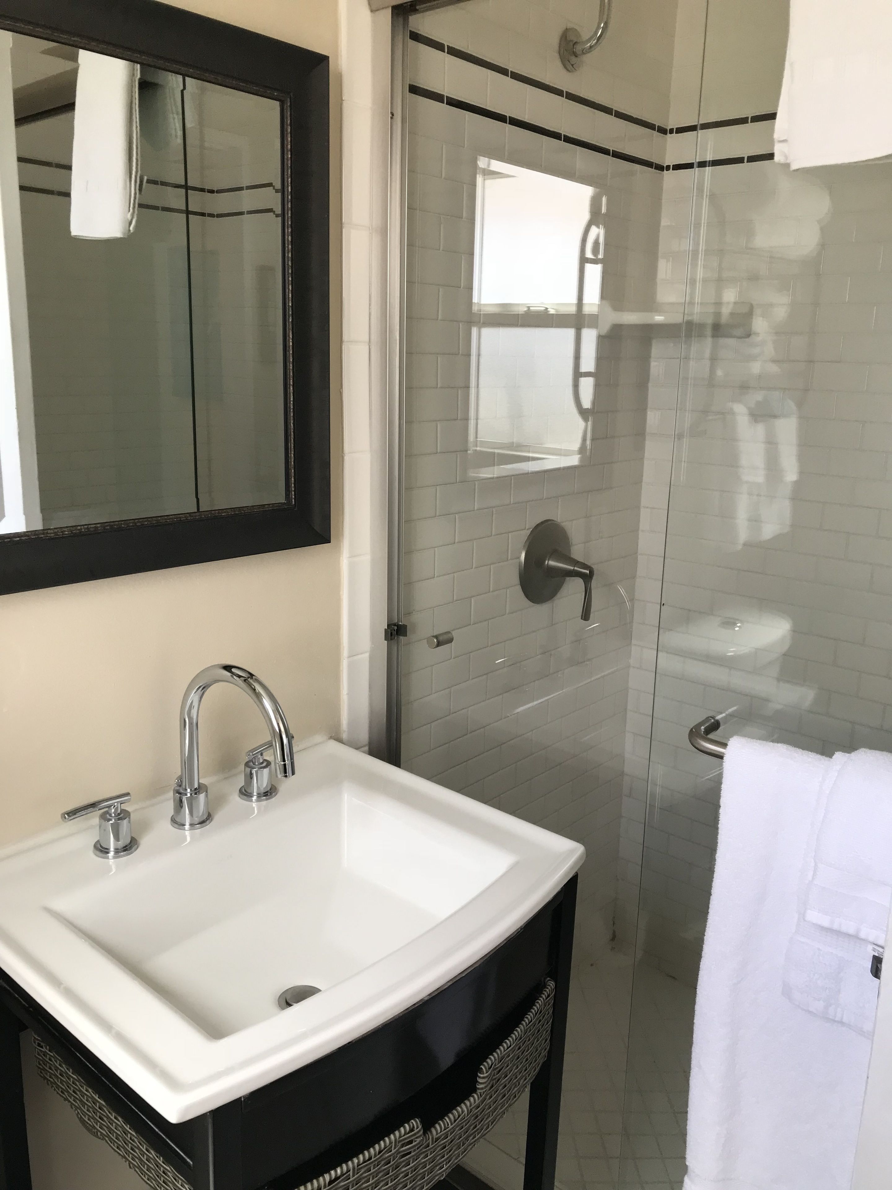A bathroom with a white sink, a mirror, and a glass-enclosed shower.