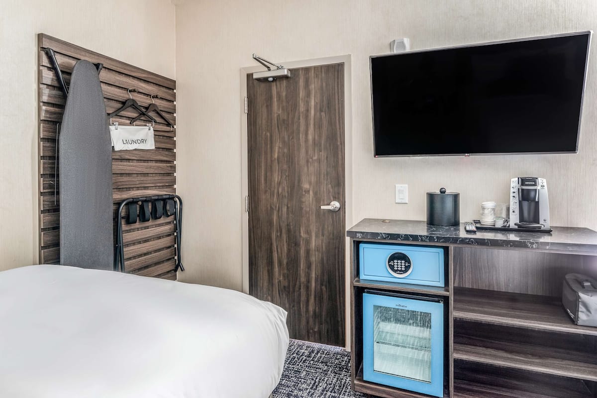 A hotel room with a bed, a TV mounted on the wall, a coffee maker, and a microwave.