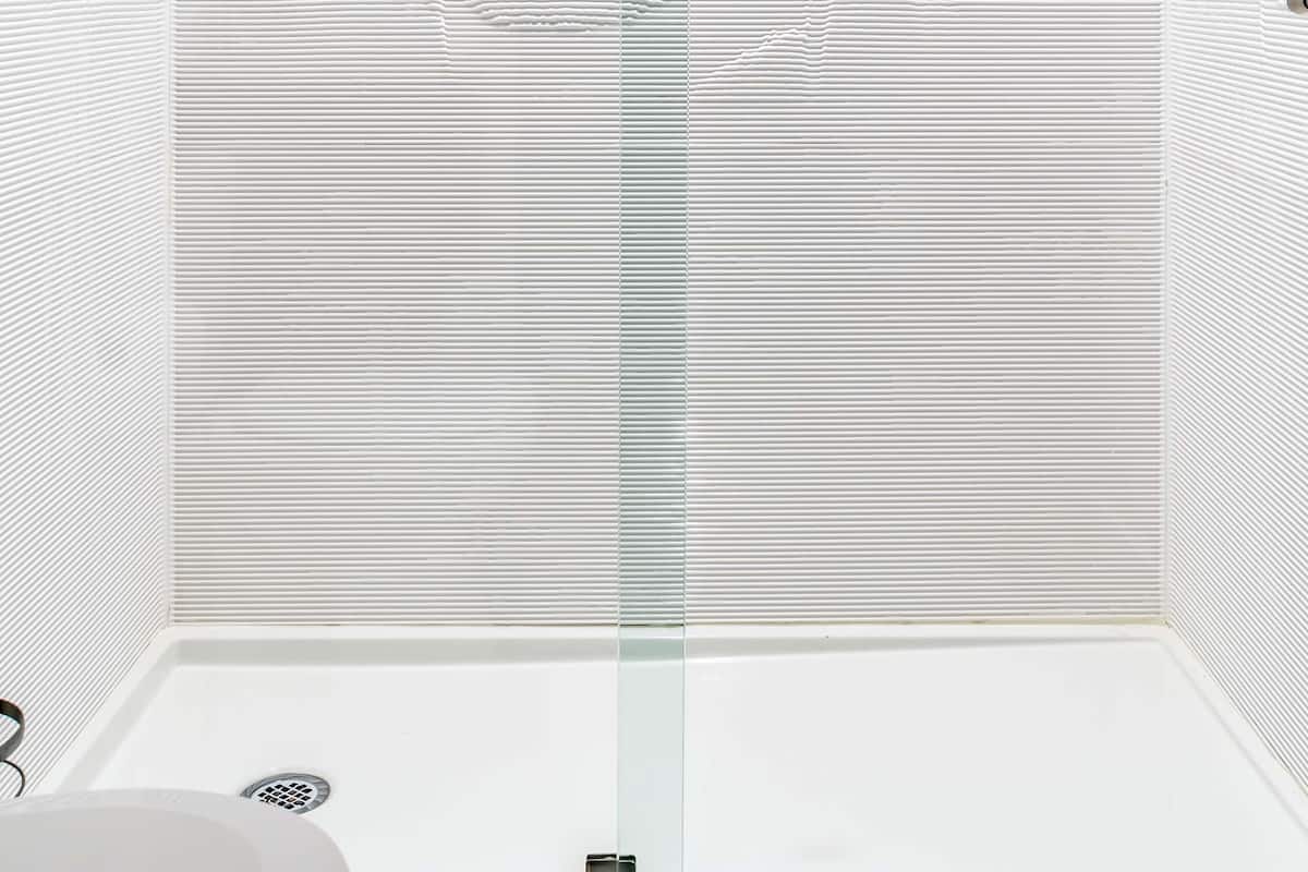 A modern bathroom with a shower, a glass door, and a towel rack.