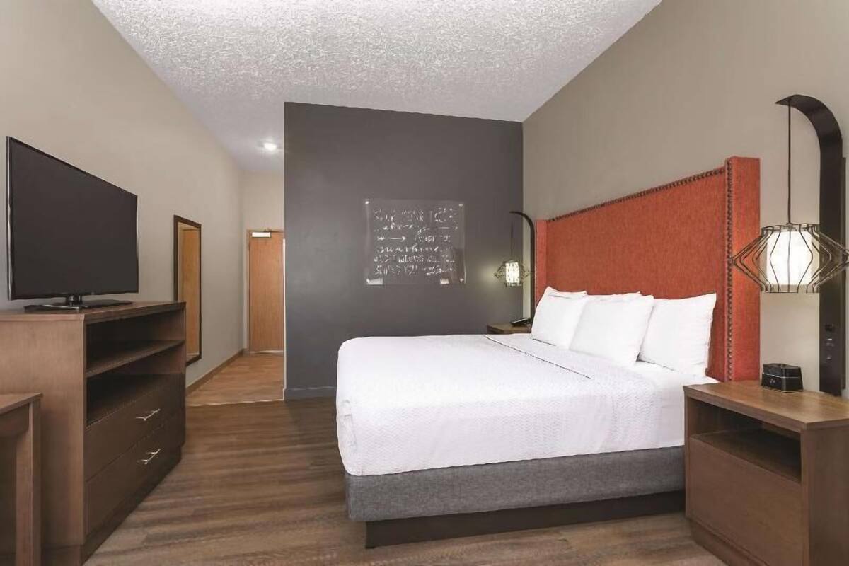 A hotel room with a bed, a TV, a desk, and a wardrobe.