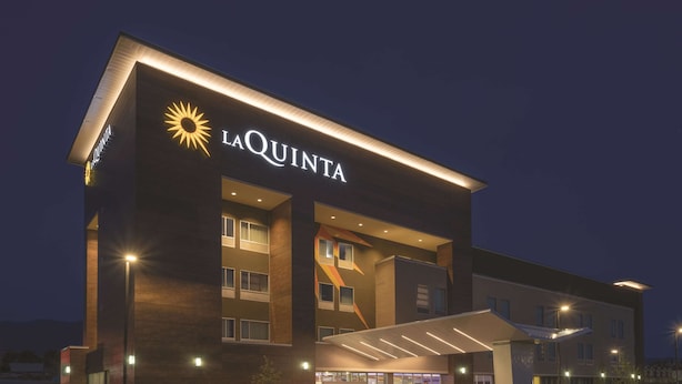 A modern hotel with a prominent 'LaQuinta' sign, multiple entry points, and a covered entrance. - La Quinta Inn & Suites by Wyndham South Jordan (South Jordan)