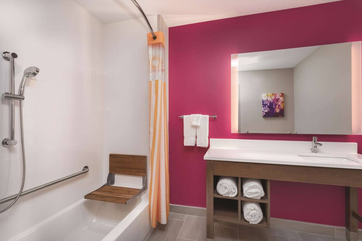 A modern bathroom with a bathtub, shower, and a vanity with a mirror.