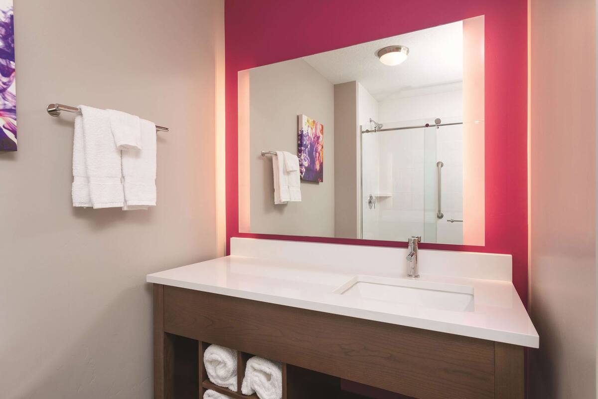 A bathroom with a white sink, a mirror with a red frame, and two towels hanging on a towel rack.