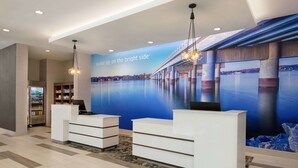 A reception area with a large mural of a bridge over water, a reception desk, and a refrigerator stocked with beverages. - La Quinta Inn & Suites by Wyndham Rock Hill (Rock Hill)