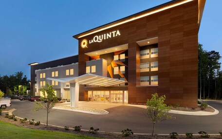 A modern hotel with a prominent 'La Quinta' sign, a covered entrance, and a landscaped driveway.