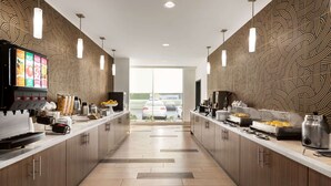 A modern kitchen with a central island, built-in appliances, and a view of the parking lot. - La Quinta Inn & Suites by Wyndham Rock Hill (Rock Hill)