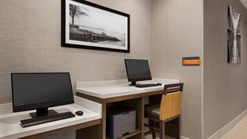 A modern office space with two desks, each with a computer and keyboard, and a chair with a woven seat.