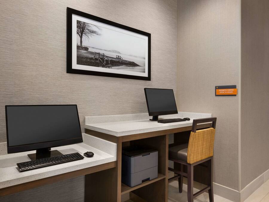 A modern office space with two desks, each with a computer and keyboard, and a chair with a woven seat.