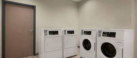 A laundry room with three white washing machines and a closed door.