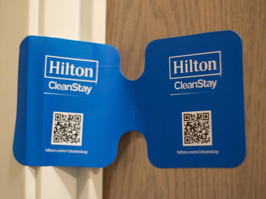 Zwei blaue Hilton CleanStay-Schilder mit QR-Codes und URLs.