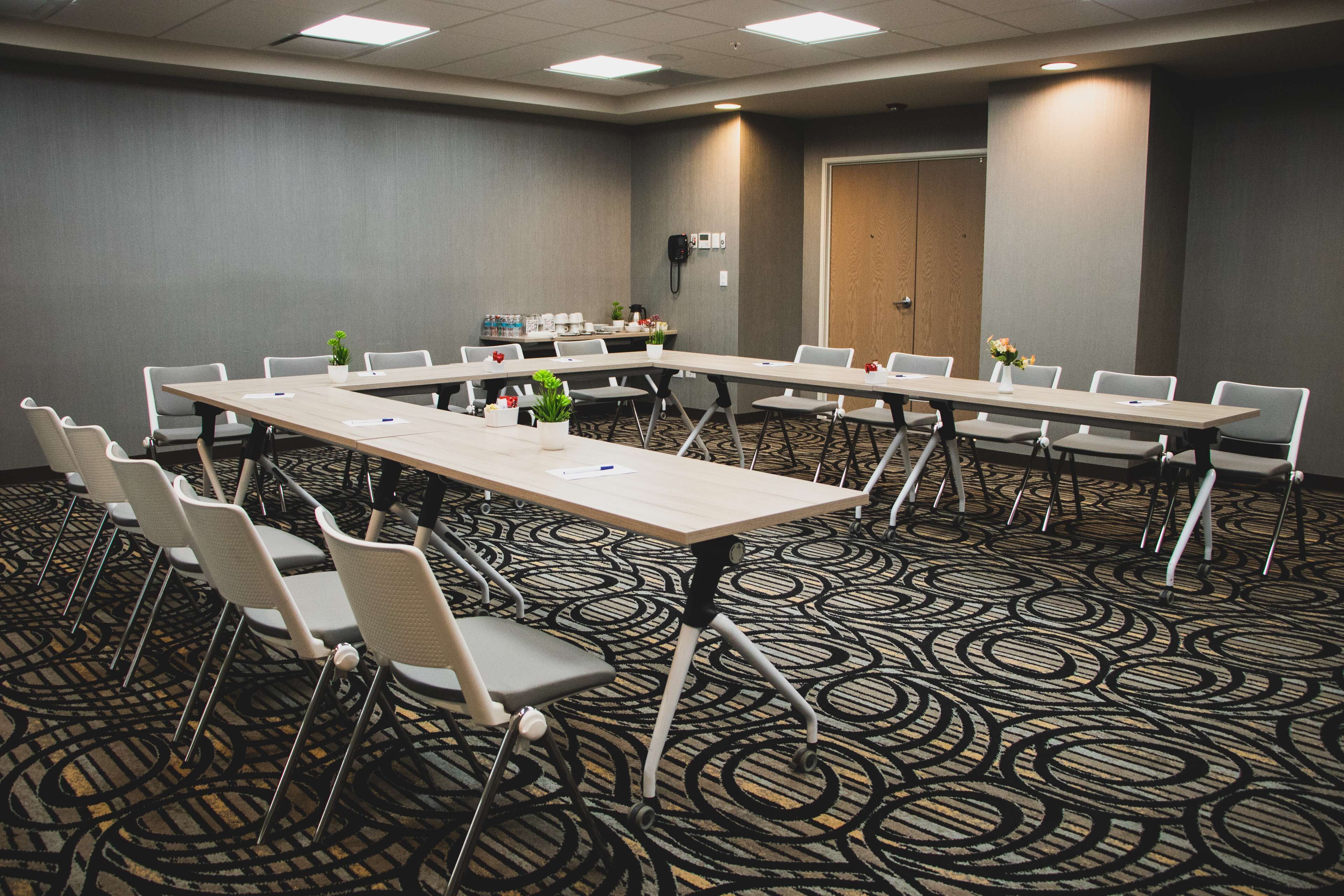 A conference room with long tables and chairs, a coffee station, and a phone on the wall.