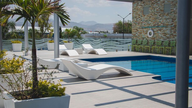 Zona de piscina en la azotea con sillones de descanso y vistas a las montañas.