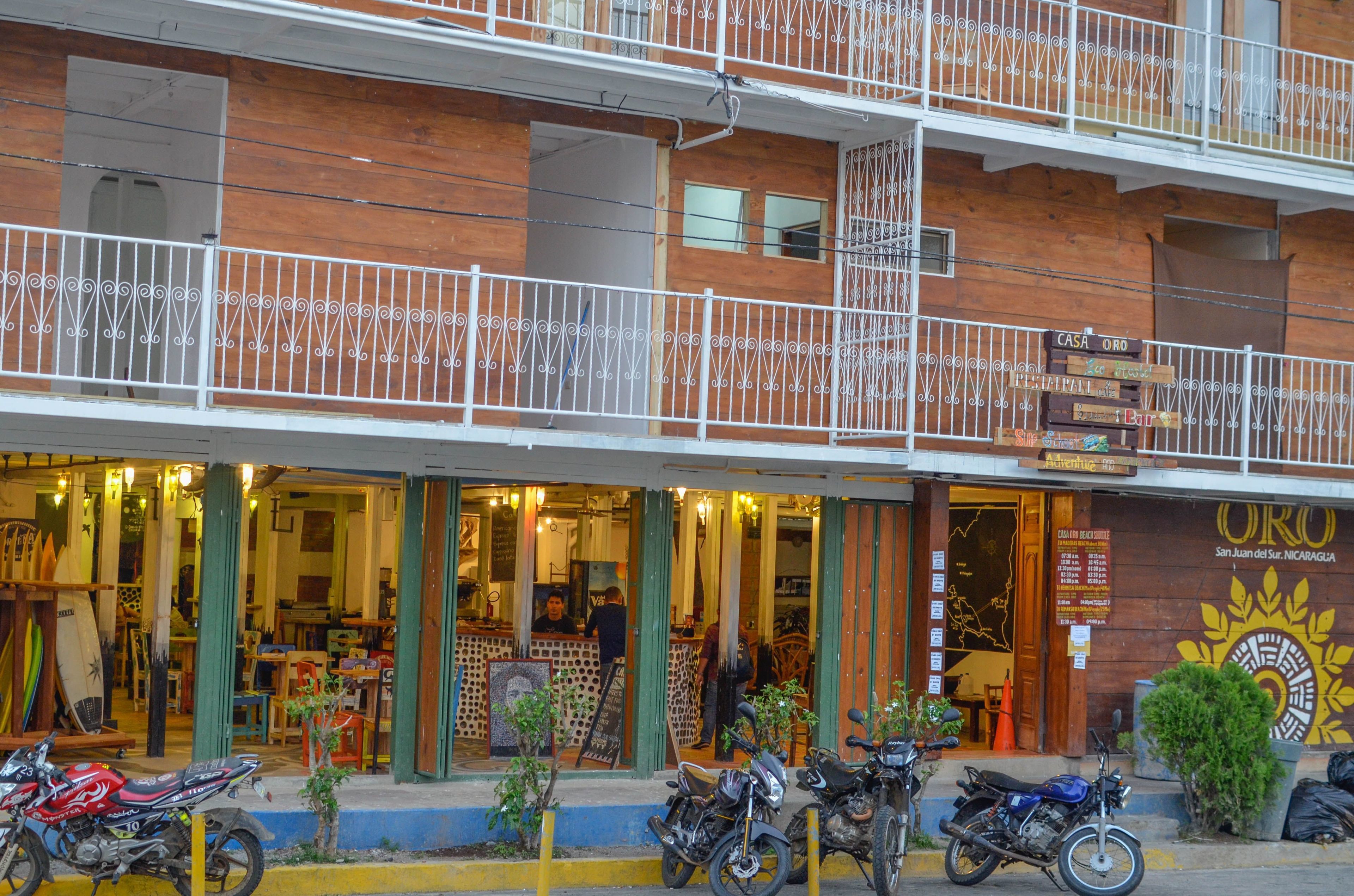 Un edificio de dos pisos con fachada de madera, balcones con barandillas blancas y un letrero que dice 'CASA ORO'.