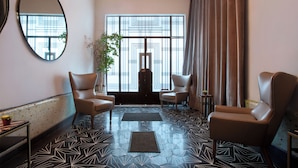 Una habitación moderna con dos sillones de cuero, un espejo grande y un piso con diseño geométrico.