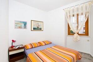 Une chambre à coucher avec un lit, une table de chevet, une lampe et deux tableaux encadrés accrochés au mur.