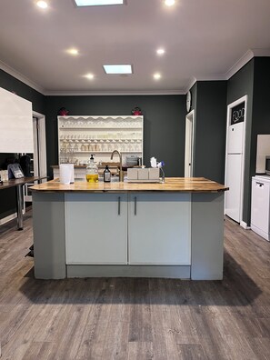 A modern kitchen with a central island, built-in shelves, and a refrigerator.