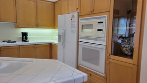 A kitchen with wooden cabinets, a refrigerator, a microwave, and a stove. - Snowcreek Resort Vacation Rental 954 (Mammoth Lakes)