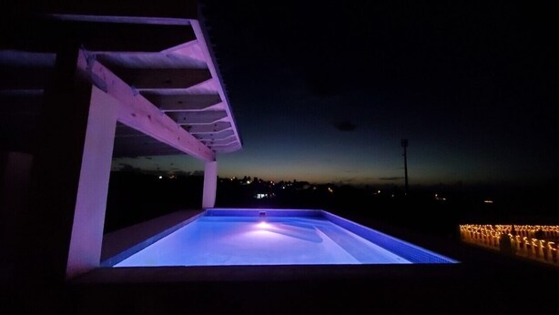 Une piscine extérieure offrant une vue sur la ville au crépuscule.