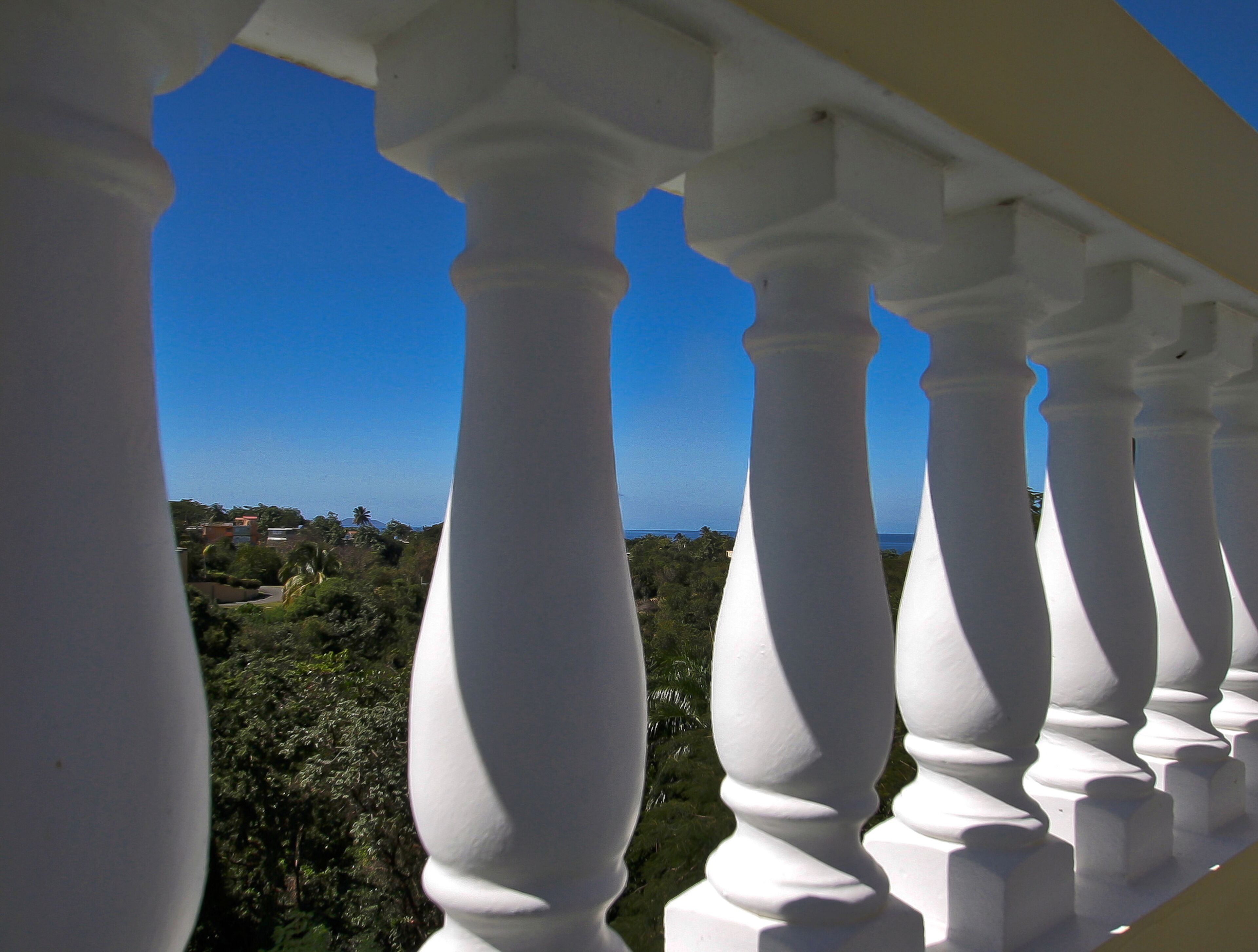A balcony with white balustrades overlooking a coastal landscape.