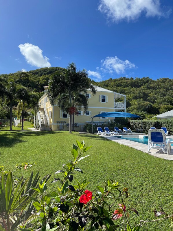 A hotel with a pool, lounge chairs, and a staircase leading to the building.