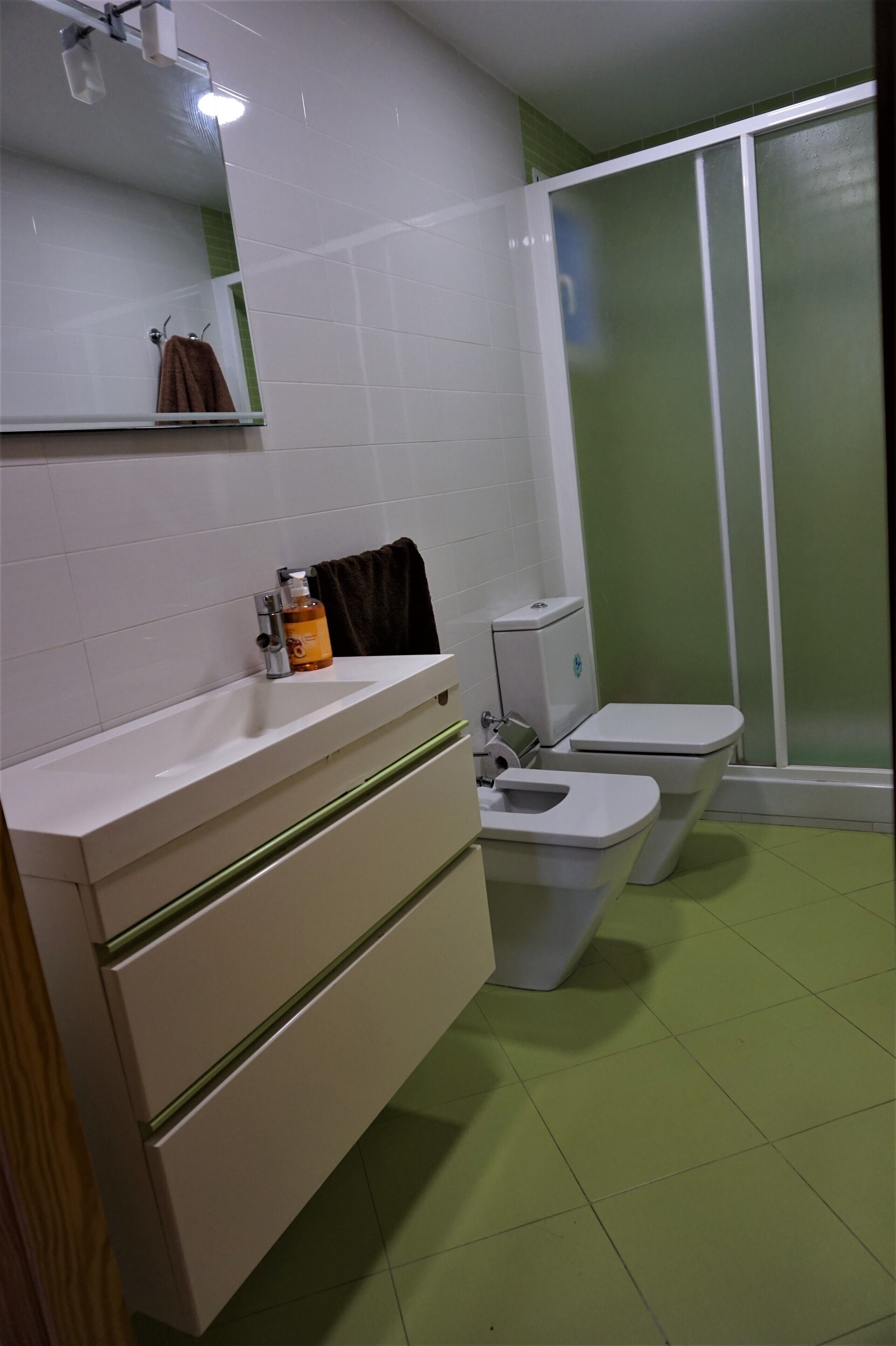 A bathroom with a white sink, mirror, and two toilets.