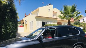 Un SUV negro estacionado frente a un edificio amarillo con techo rojo y una pequeña torre.