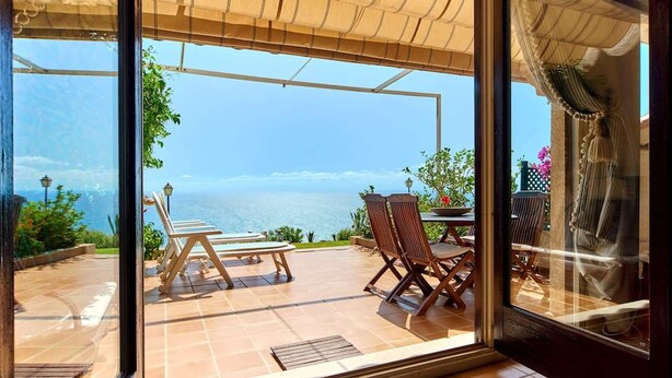 Pátio com mesa e cadeiras, com vista panorâmica do mar.