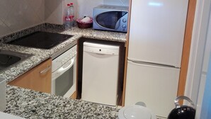 Cocina compacta con microondas integrado, lavavajillas y refrigerador.