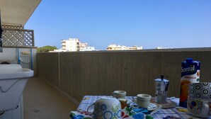 Un balcón con una mesa lista para el desayuno, que incluye una cafetera, tazas y una botella de zumo de Santal Albicocca.
