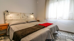 A bedroom with a bed, a nightstand, a lamp, a window with curtains, and patterned floor tiles. - The best terrace of the Serranía de Ronda, Emerald Pool: Casa Martijín (Jimera de Líbar)