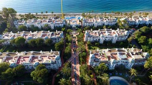 Un hôtel situé sur la côte, composé de plusieurs bâtiments blancs disposés selon un plan en forme de grille, avec des balcons et une cour intérieure centrale.