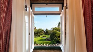 Un umbral abierto que da a un jardín cuidado y una vista despejada del cielo y la vegetación circundante.
