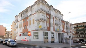 Um edifício de vários andares com varandas, um aviso de 'Proibido Entrar' e um letreiro com o nome 'Charly' no andar térreo.