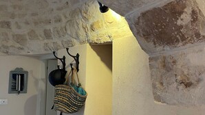 Une alcôve aux murs de pierre, agrémentée d’un panier tressé suspendu et d’un pot.
