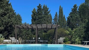 Une piscine aux eaux cristallines, agrémentée de chaises longues et d’une pergola en arrière-plan.
