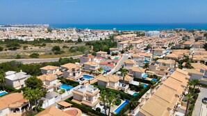 Un quartier résidentiel avec des maisons, dont certaines sont équipées de panneaux solaires, et qui offre une vue dégagée sur la mer.