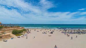 Une plage avec des transats et des parasols, un mur de pierre et une vue sur la mer.