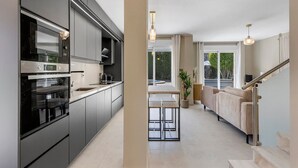 Une cuisine moderne dotée d’appareils électroménagers intégrés et d’un coin repas comprenant un canapé et une table.