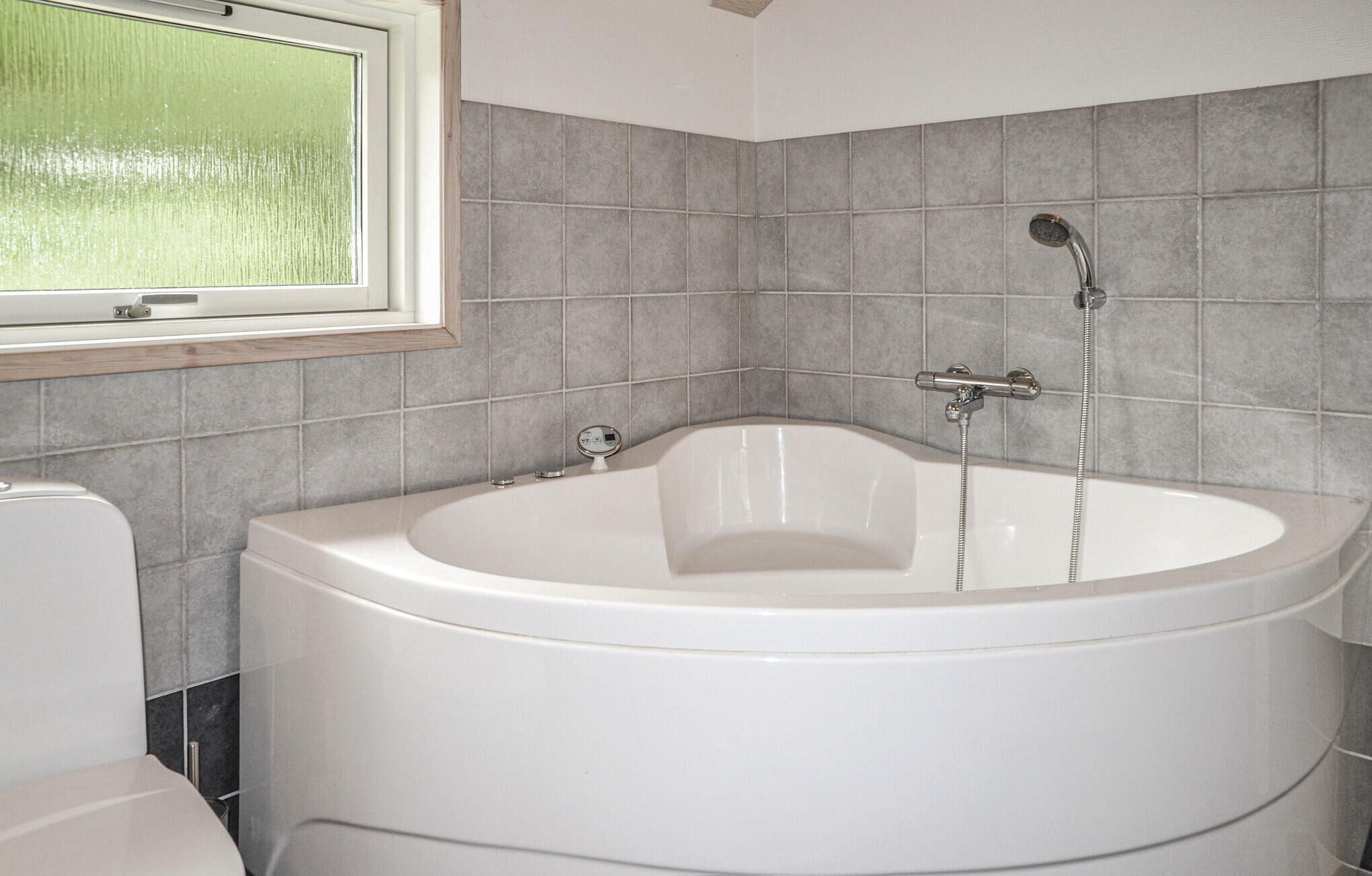 A bathroom with a freestanding bathtub, a toilet, and a window.