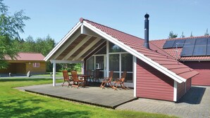 A modern house with a sloped roof, a covered patio with wooden furniture, and solar panels on the roof. - Nice home in Oksbøl with sauna (Oksbøl)