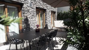 Une maison en pierre avec une terrasse, une table et des chaises.