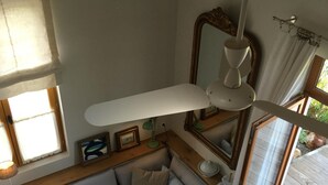 Une pièce chaleureuse avec un canapé de couleur claire, une petite table, une lampe sur pied et un grand miroir.