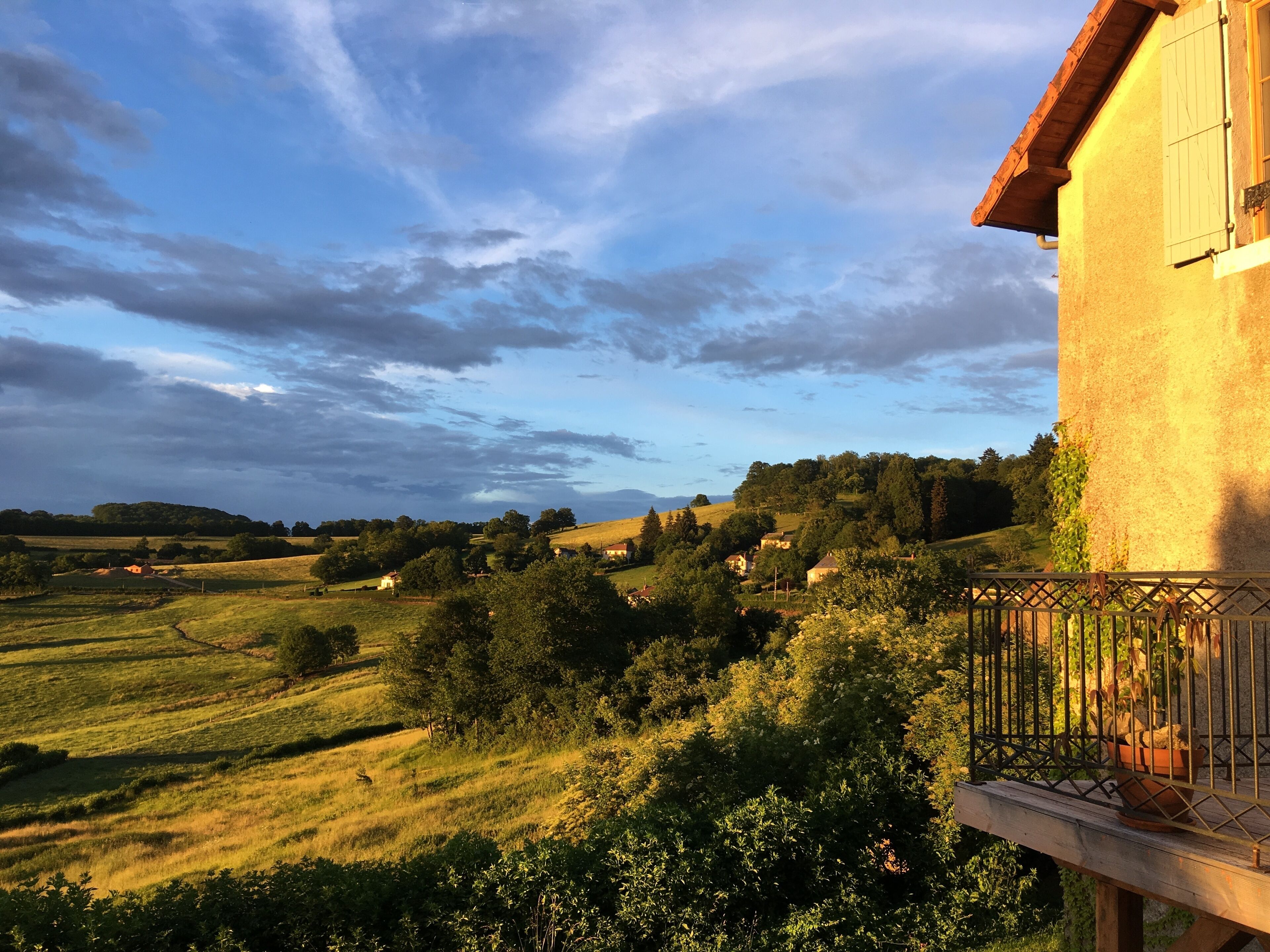 A rural landscape with rolling hills, a clear sky, and a building with a balcony.