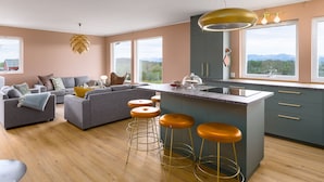 Una cocina moderna con una isla central, taburetes de bar y vistas al exterior.