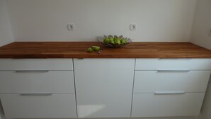 Una cocina con armarios blancos, encimera de madera y un tazón de manzanas verdes.