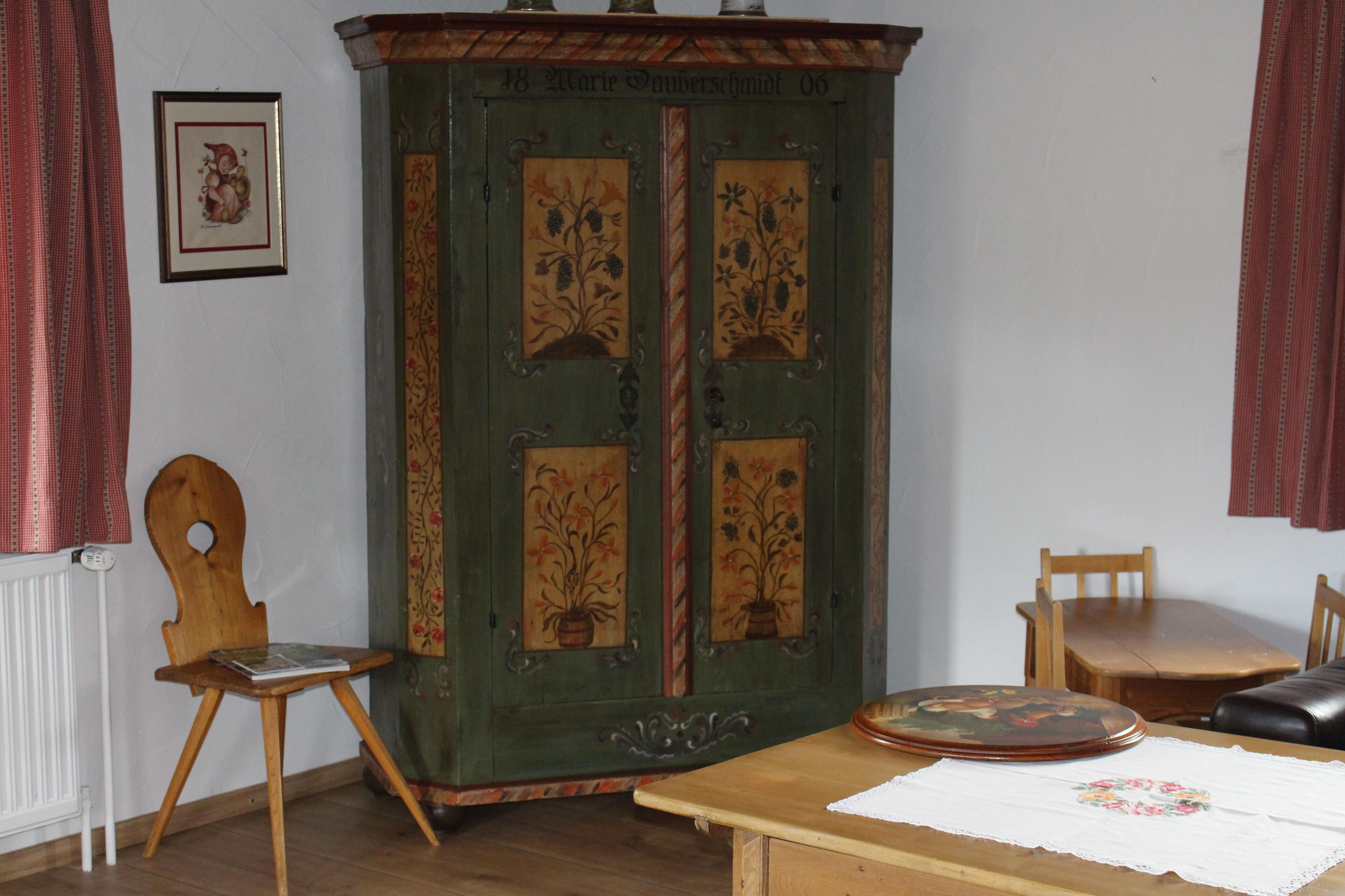 Una habitación con un armario de madera, una silla, una mesa y un radiador.
