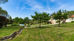 Una proprietà residenziale con piscina, un pergolato e un vialetto in pietra che conduce a una casa con tetto in tegole.