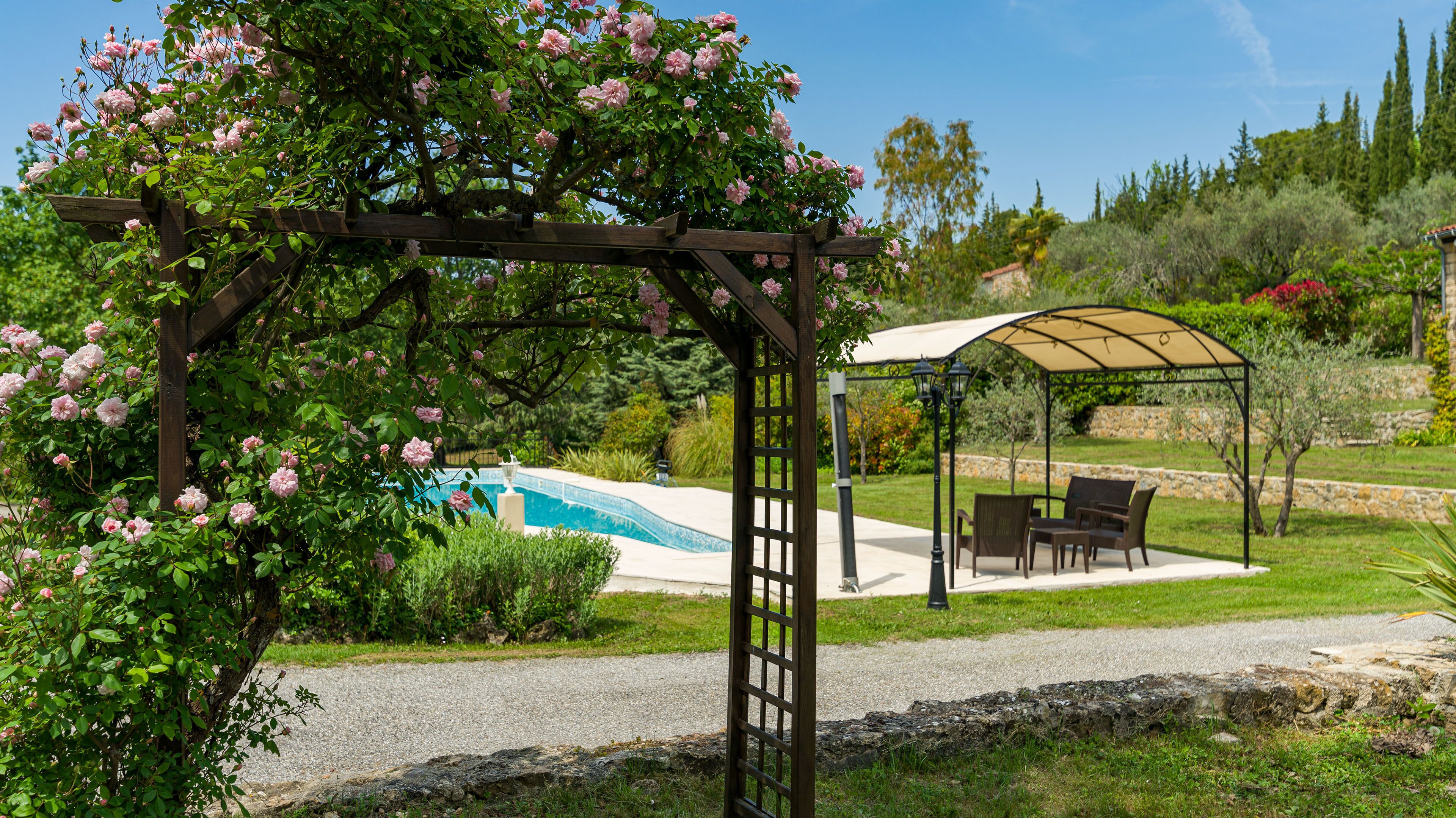 Um jardim com pérgola, piscina e área de estar externa.